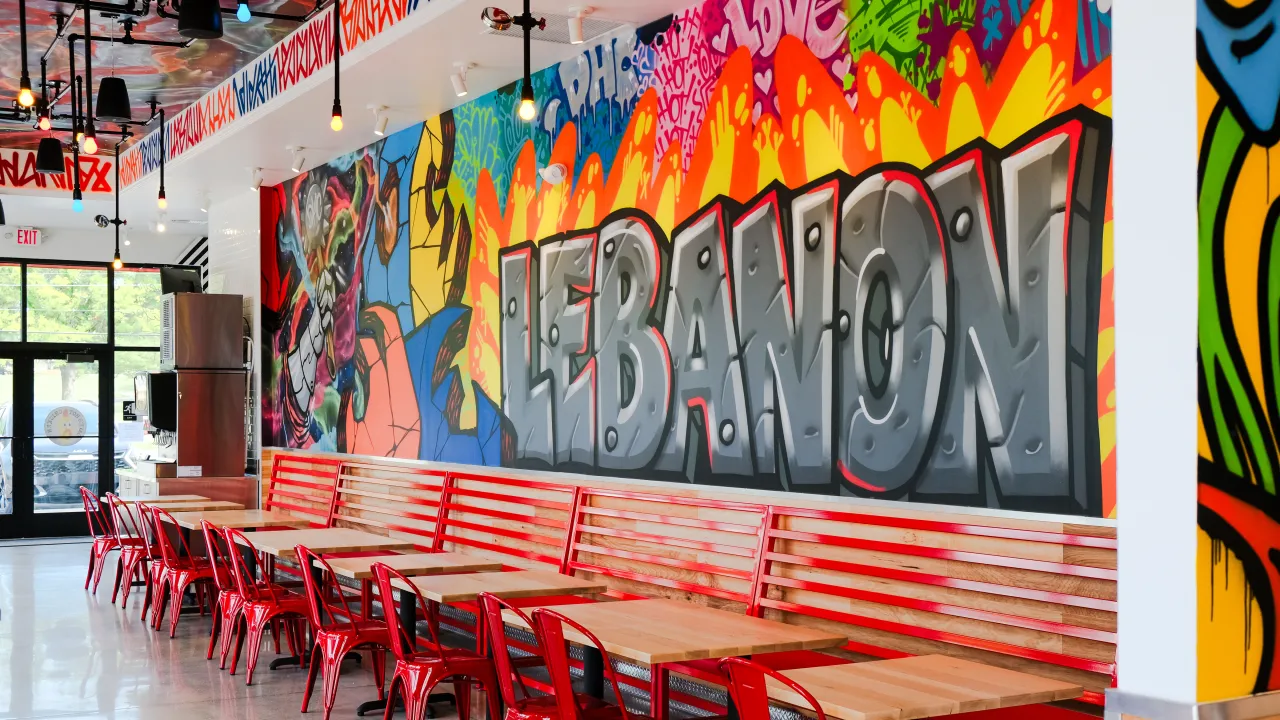 Interior view of Dave's Hot Chicken on Quentin Rd, Lebanon, PA, showcasing vibrant mural and red seating.
