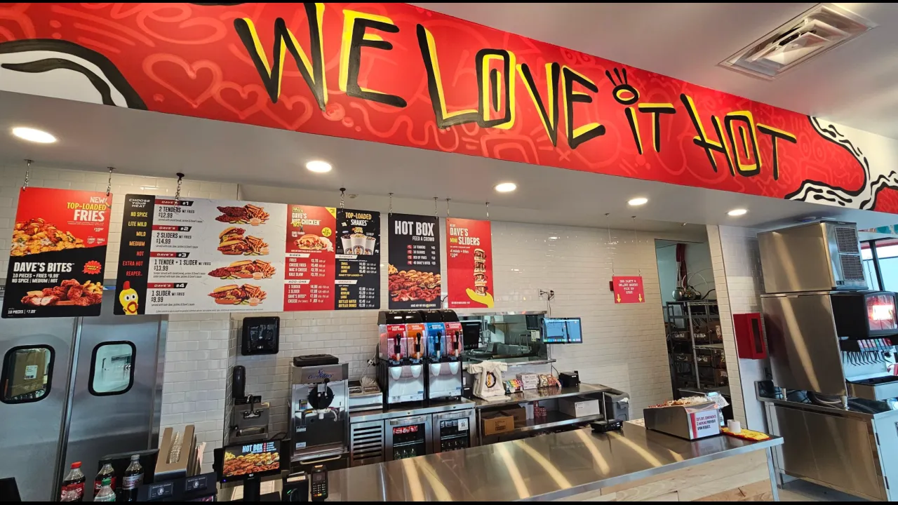 Interior view of Dave's Hot Chicken on E. Ridge Rd, Rochester, NY, showcasing colorful menu boards and a vibrant ambiance.