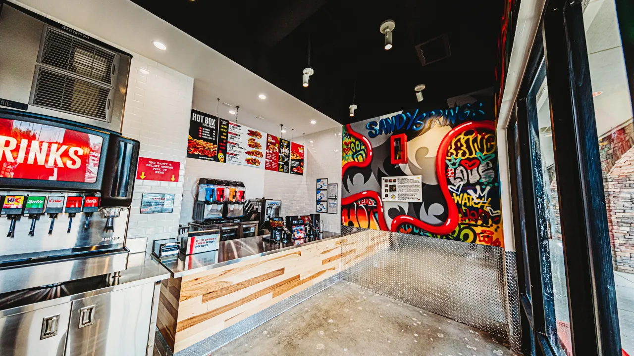 Interior view of Dave's Hot Chicken on Roswell Road, Sandy Springs, GA, featuring vibrant murals and modern counter design.