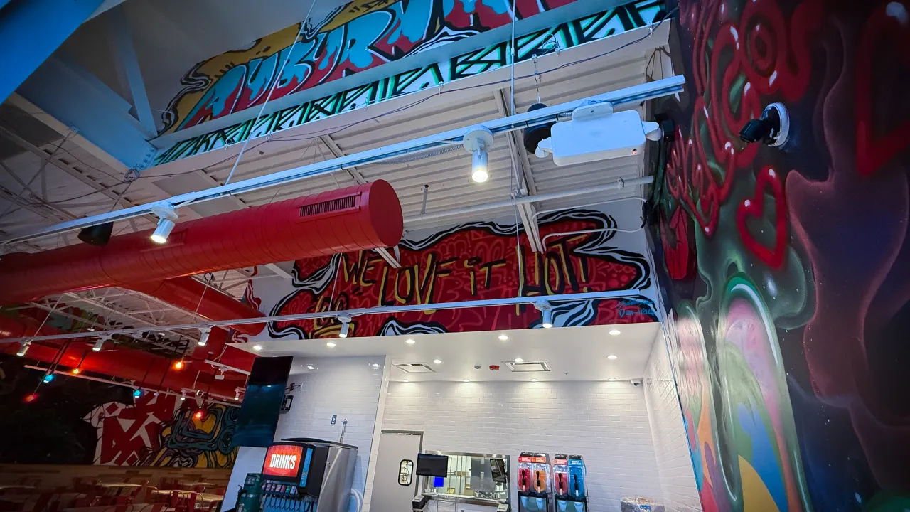 Interior view of Dave's Hot Chicken at 2031 N. Squirrel Rd, Auburn Hills, MI, showcasing vibrant murals and a cozy ambiance.