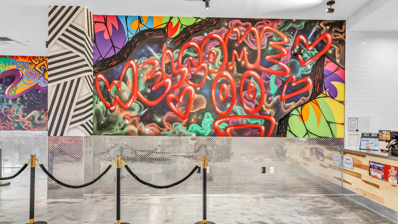 Interior view of Dave's Hot Chicken at 2333 Summer St, Stamford, CT, showcasing vibrant graffiti art and a sleek counter.