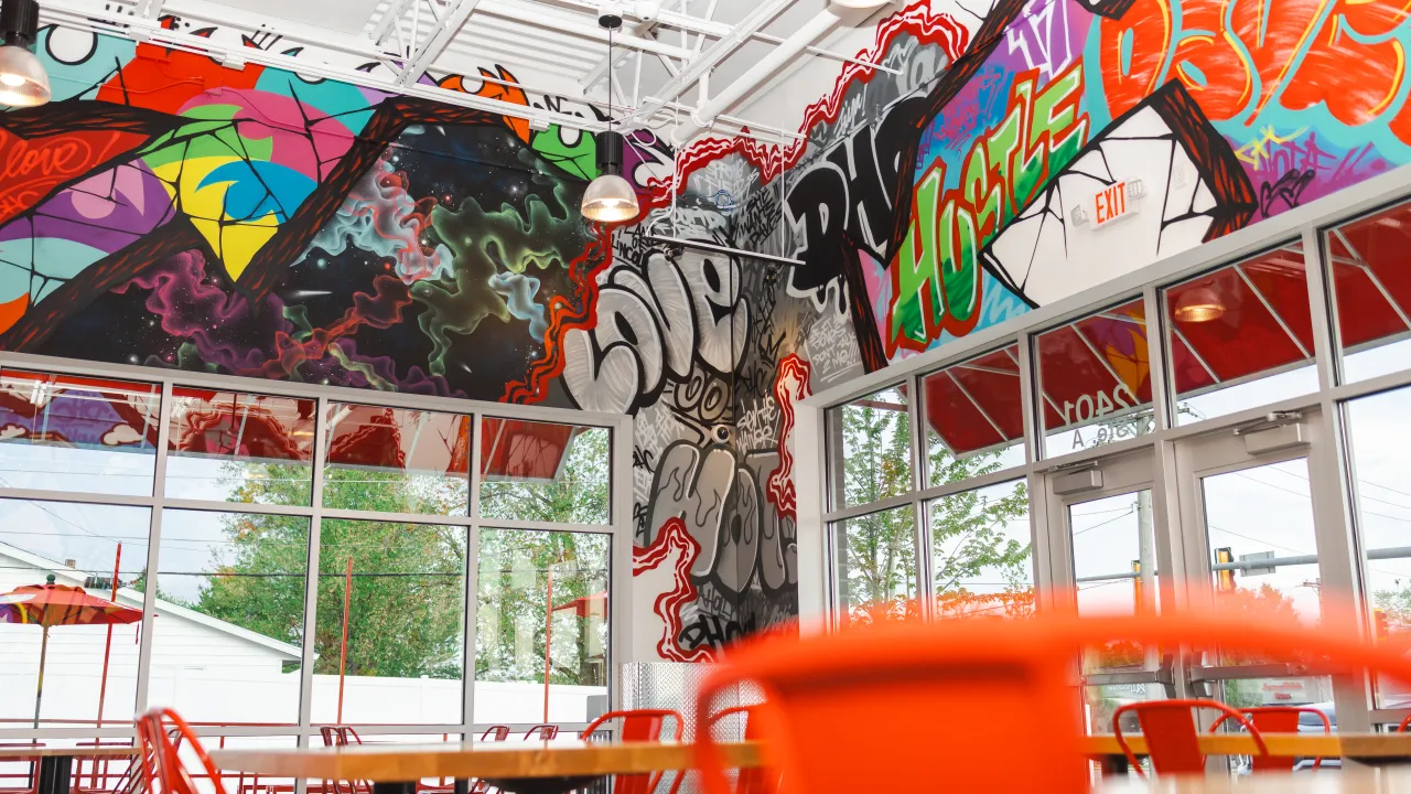 Interior view of Dave's Hot Chicken at 2401 Wabash Ave, Springfield, IL, showcasing vibrant graffiti murals and bright seating.
