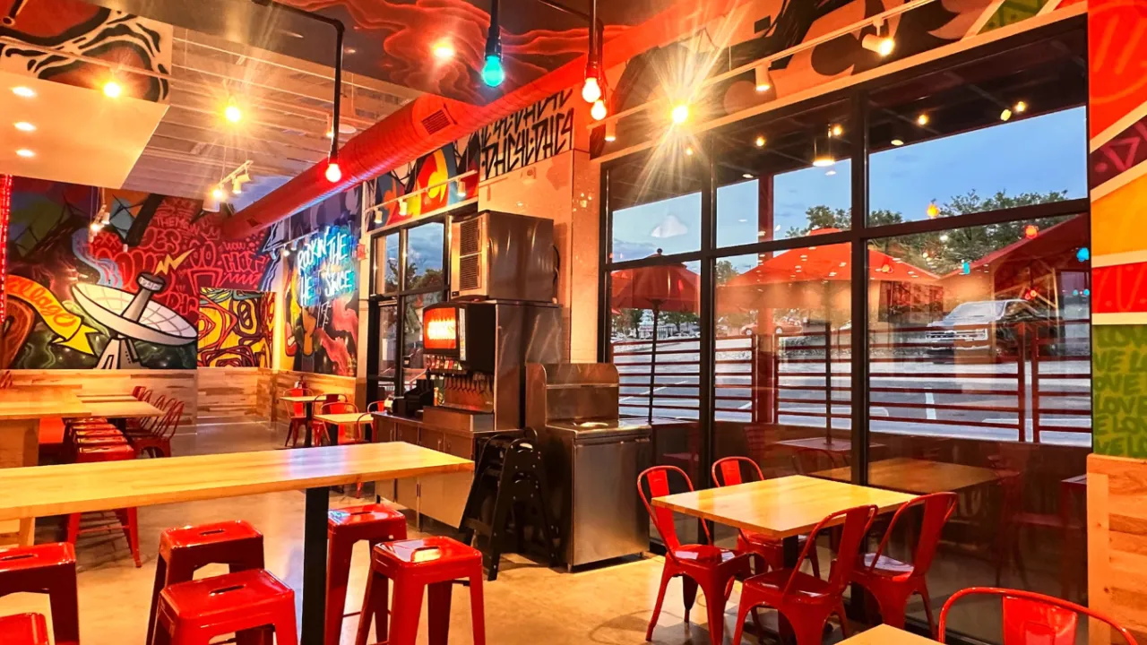 Interior view of Dave's Hot Chicken on E. Arapahoe Rd, Greenwood Village, CO, showcasing vibrant murals and red seating.