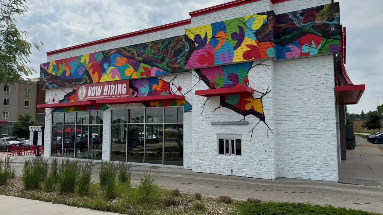 Exterior view of Dave's Hot Chicken on Broadway Avenue South, Rochester, MN, showcasing vibrant murals and bold signage.