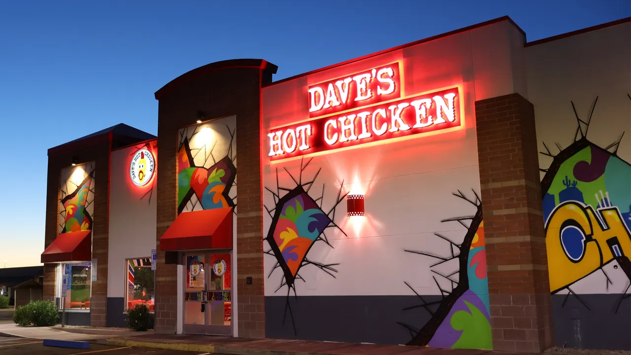 Exterior view of Dave's Hot Chicken on W. Chandler Blvd, Chandler, AZ, featuring vibrant murals and illuminated signage.
