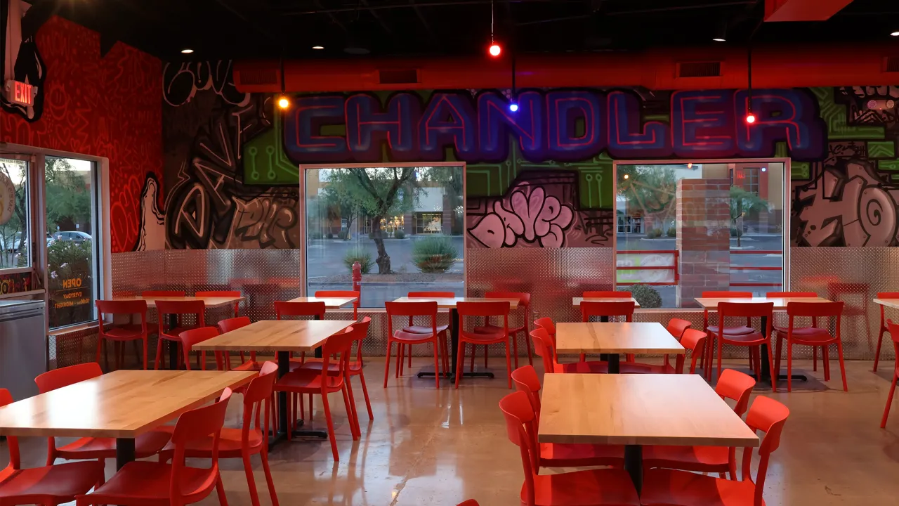 Interior view of Dave's Hot Chicken on W. Chandler Blvd, Chandler, AZ, featuring vibrant murals and red furniture.