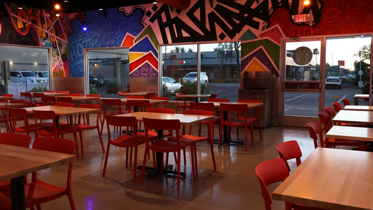 Interior view of Dave's Hot Chicken on W. Chandler Blvd, Chandler, AZ, showcasing vibrant graffiti murals and red furniture.