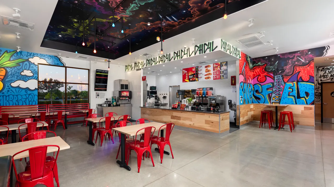 Interior view of Dave's Hot Chicken at 5291 Gosford Rd, Bakersfield, CA, showcasing vibrant murals and red furniture.