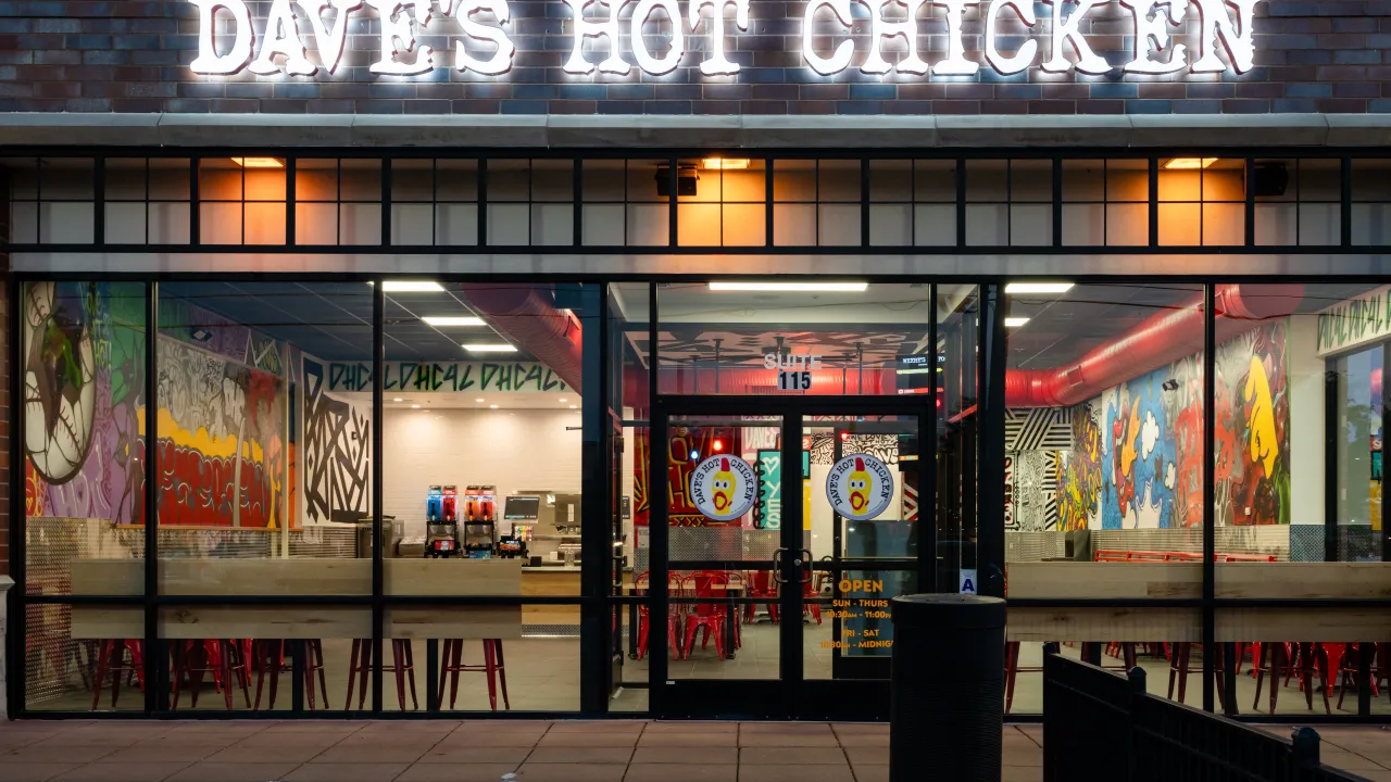 Exterior view of Dave's Hot Chicken on Chesterfield Airport Rd, Chesterfield, MO, showcasing vibrant murals and bright signage.