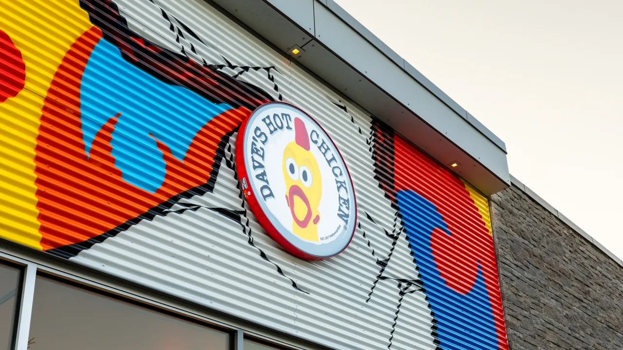 Exterior view of Dave's Hot Chicken at 409 E. Hills Blvd. SE, Calgary, AB, featuring vibrant murals and prominent signage.
