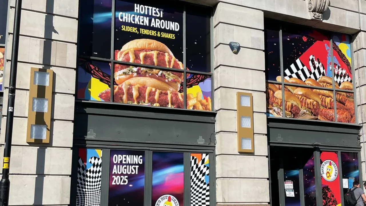 Exterior view of Dave's Hot Chicken on Withy Grove, Manchester, M4 2BS, showcasing vibrant signage and colorful window displays.