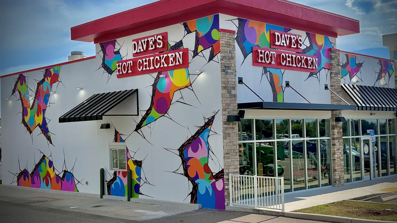 Exterior view of Dave's Hot Chicken on Big Bend Road, Riverview, FL, showcasing vibrant murals and bold signage.