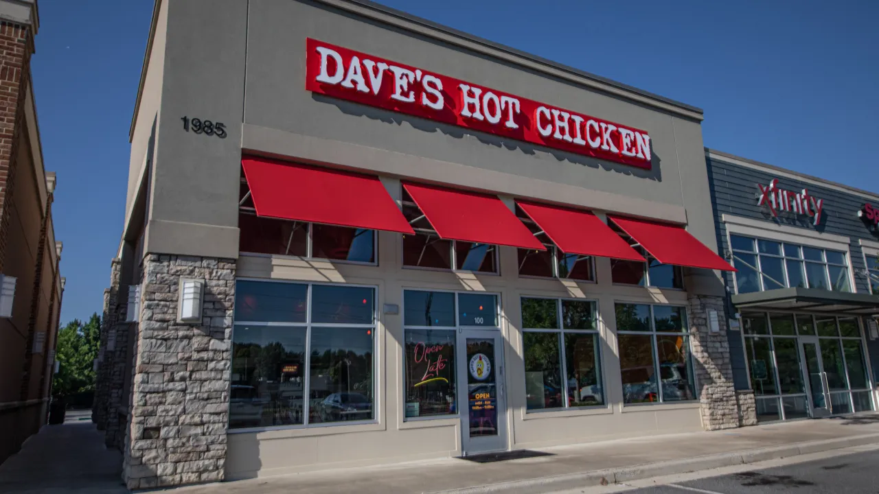 Exterior view of Dave's Hot Chicken at 1985 Cobb Pkwy NW, Kennesaw, GA, showcasing vibrant red awnings and bold signage.