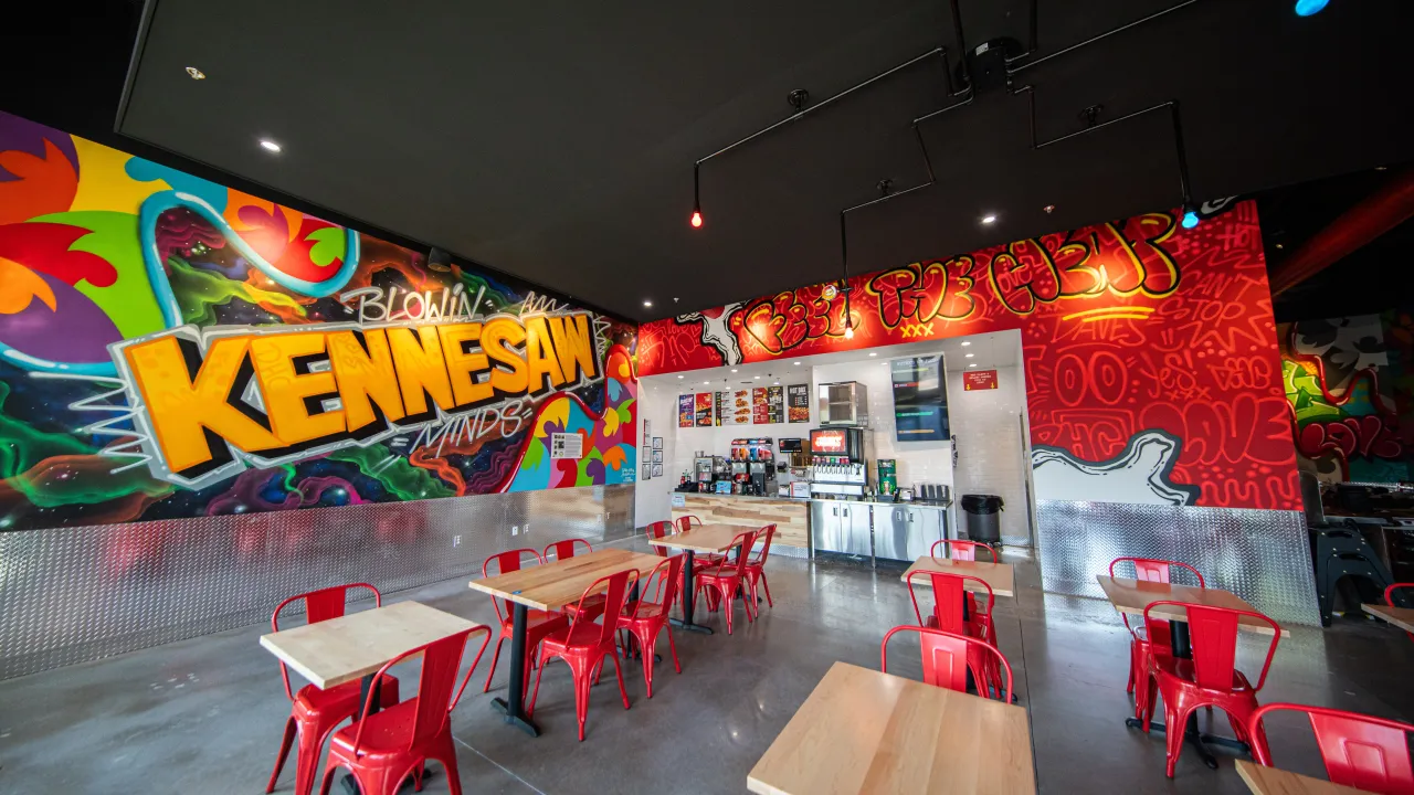 Interior view of Dave's Hot Chicken on Cobb Pkwy NW, Kennesaw, GA, showcasing vibrant murals and modern seating.