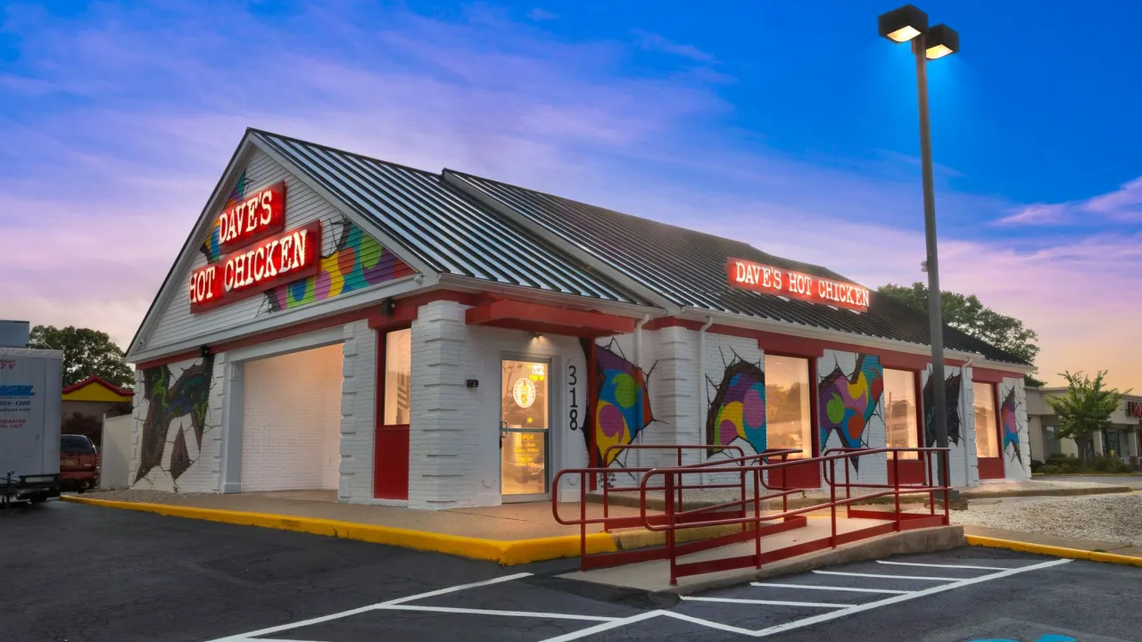 Exterior view of Dave's Hot Chicken at 318 North Dupont Hwy, Dover, DE, showcasing colorful murals and bright signage.