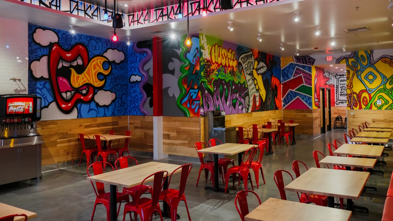 Interior view of Dave’s Hot Chicken at 520 Gateway Ave, Chambersburg, PA, featuring vibrant murals and red seating.