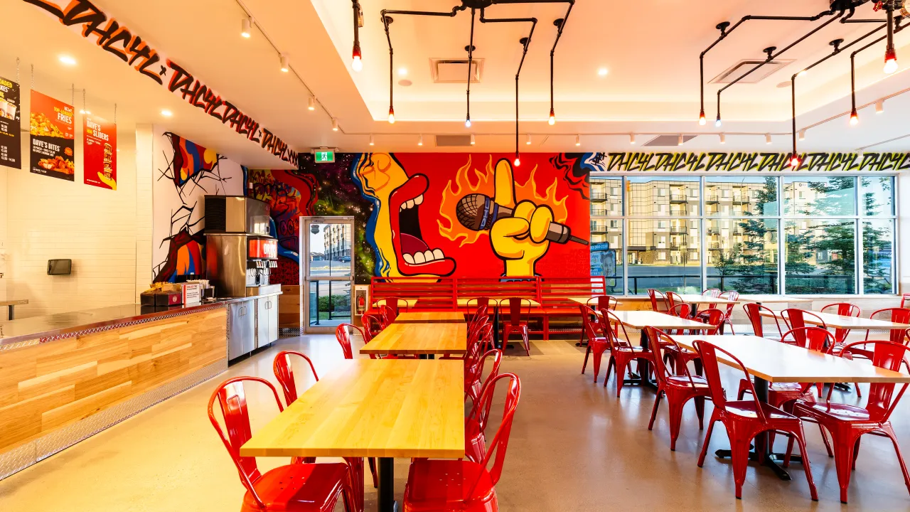 Interior view of Dave's Hot Chicken on Sarcee Trail NW, Calgary, AB, featuring vibrant murals and red seating.