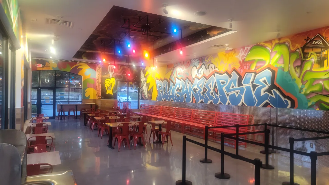 Interior view of Dave's Hot Chicken at 2521 South Rd, Poughkeepsie, NY, showcasing vibrant murals and red seating.