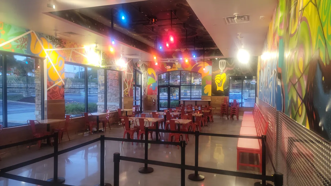 Interior view of Dave's Hot Chicken on South Rd, Poughkeepsie, NY, showcasing vibrant murals and red seating.