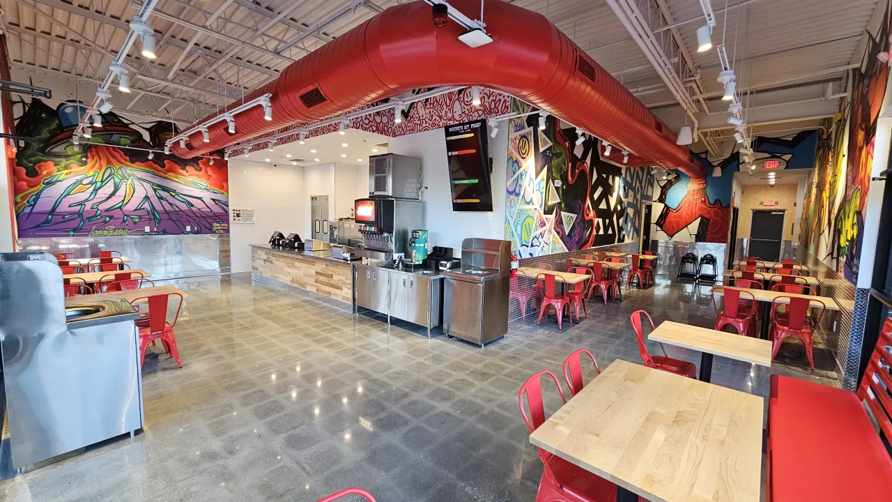 Interior view of Dave's Hot Chicken on Chipman Rd, Lee's Summit, MO, showcasing vibrant murals and red seating.