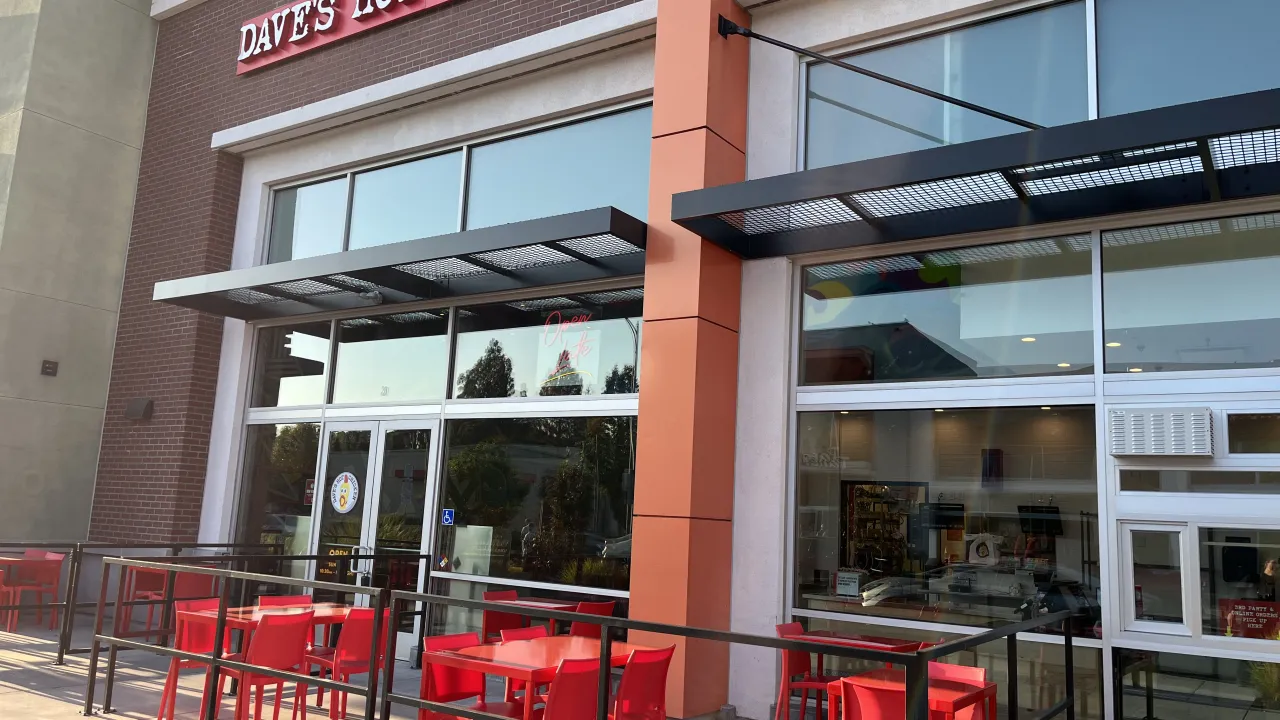 Exterior view of Dave's Hot Chicken on Cottle Road, San Jose, CA, featuring large windows and vibrant red seating.