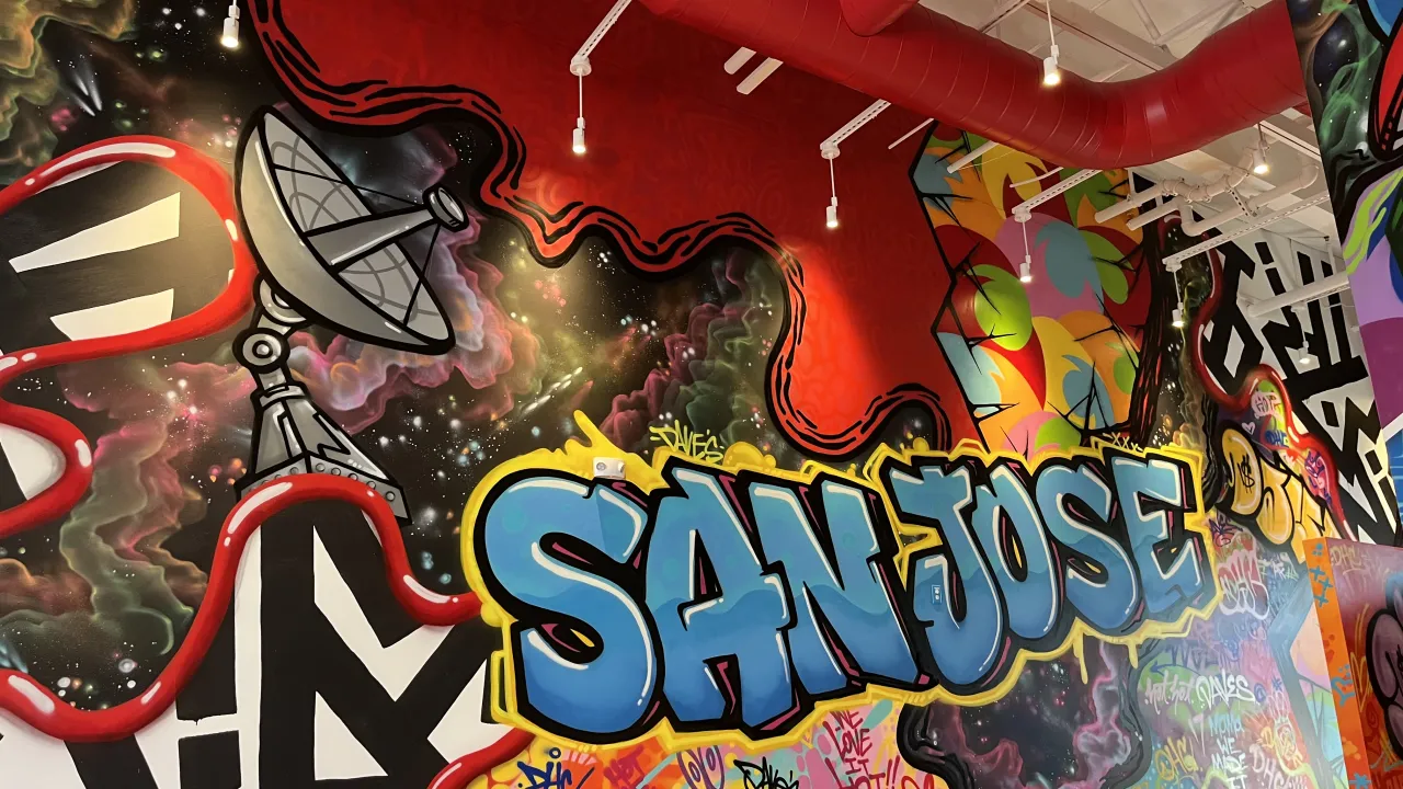 Interior view of Dave's Hot Chicken on Cottle Road, San Jose, CA, featuring vibrant murals and colorful graffiti art.