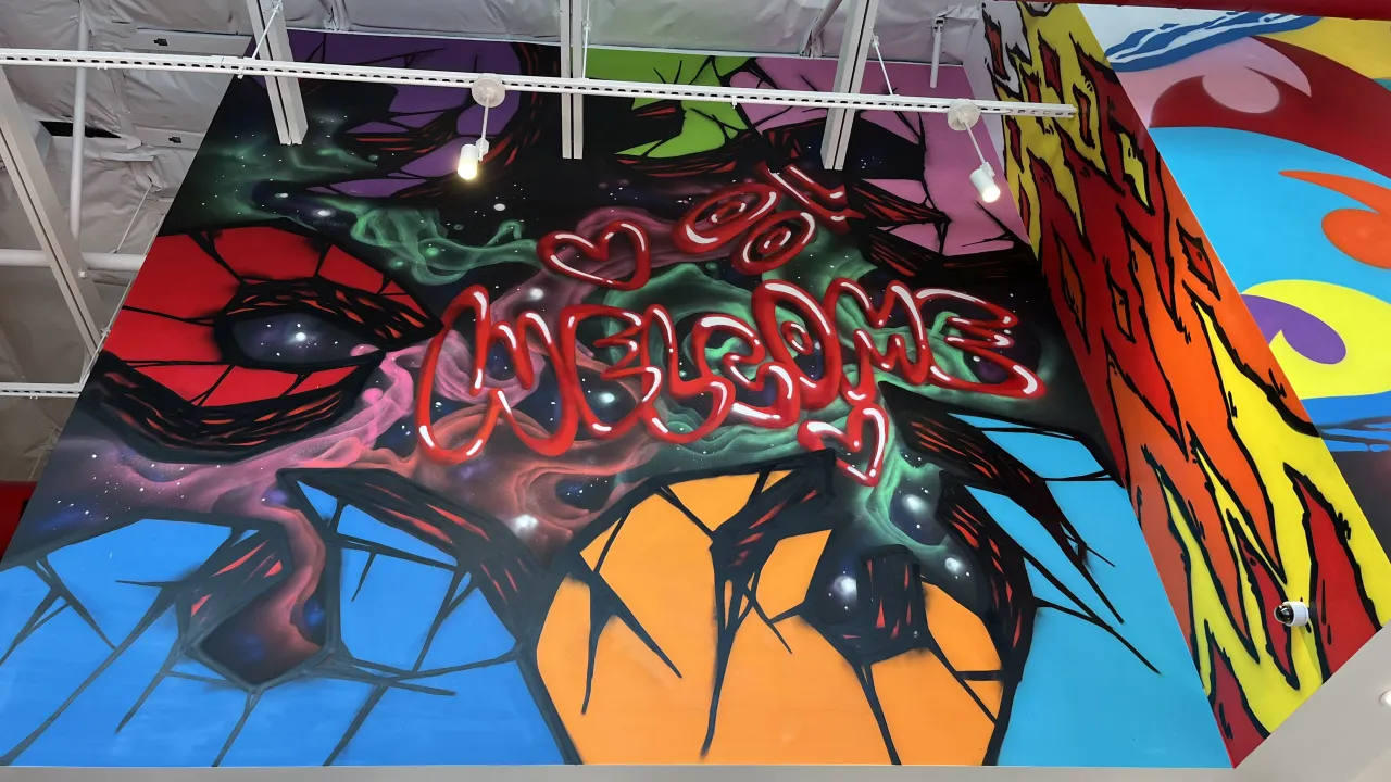 Colorful ceiling mural with 'Welcome' at Dave's Hot Chicken on Cottle Road, San Jose, CA, showcasing vibrant art and ambiance.