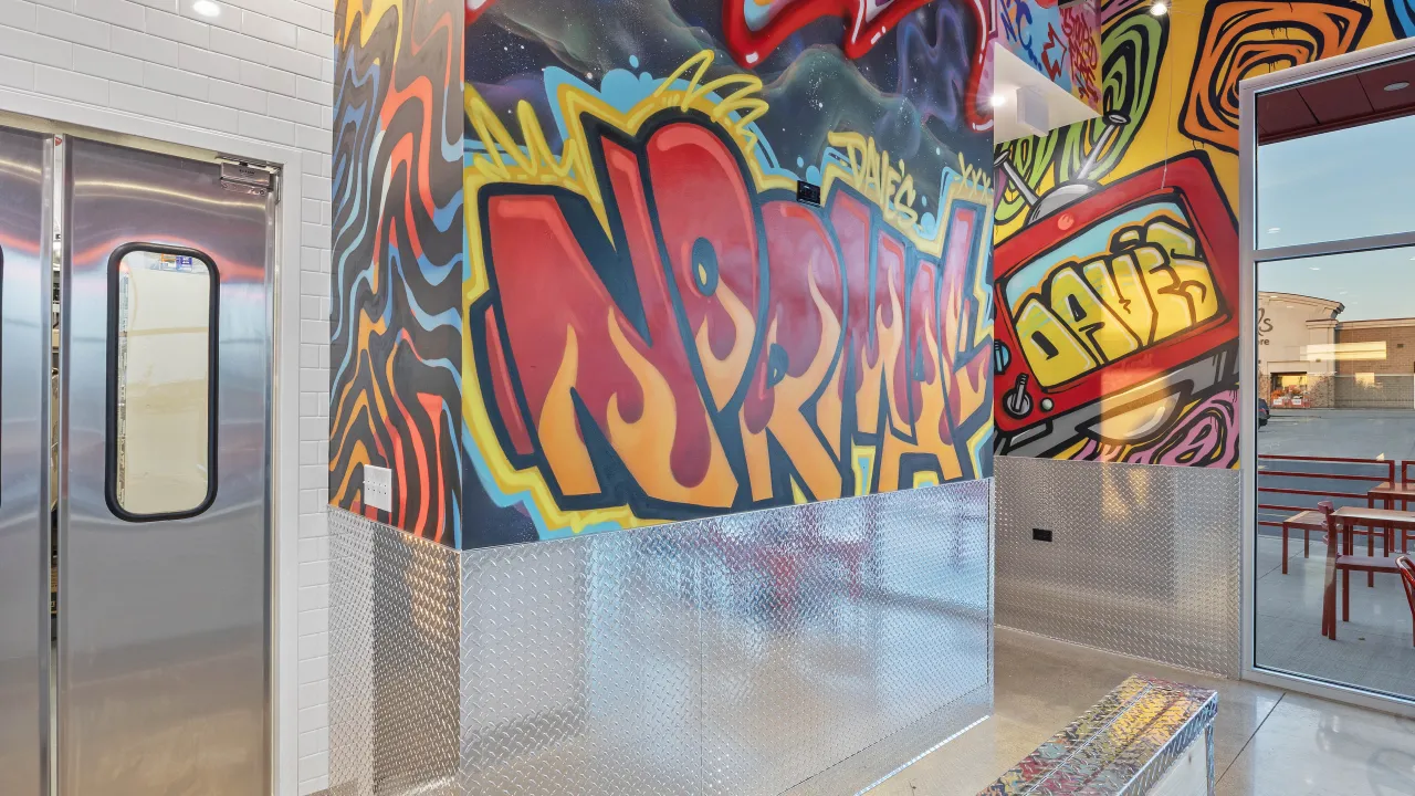 Interior view of Dave's Hot Chicken at 200 Greenbrier Dr, Normal, IL, showcasing vibrant murals and a modern ambiance.