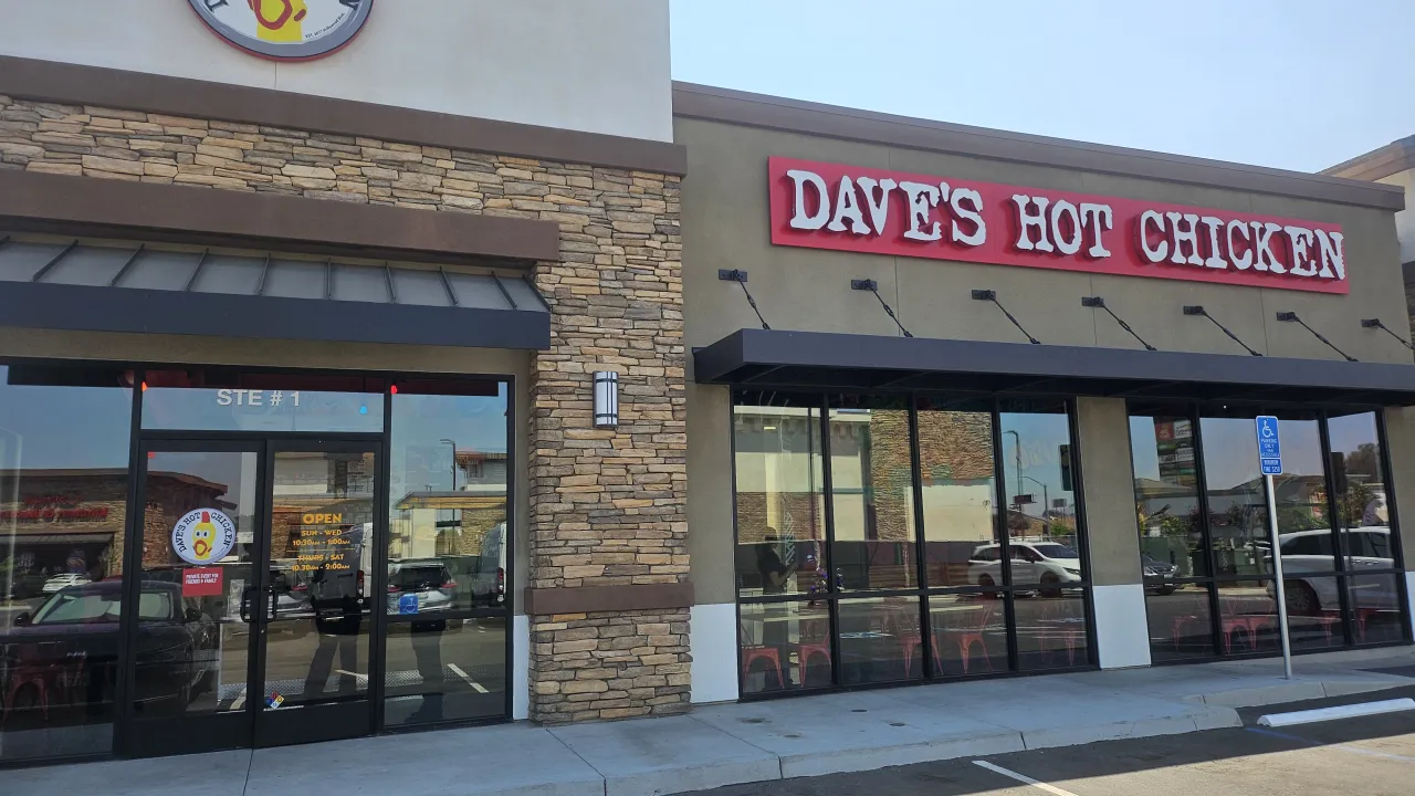 Exterior view of Dave's Hot Chicken on Greenspot Rd, Highland, CA, showcasing bold red signage and modern stone accents.