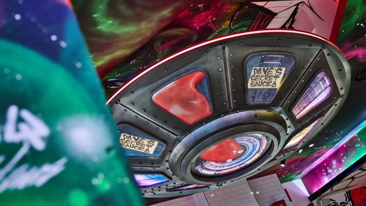 Interior view of Dave's Hot Chicken on 56 New Street, Birmingham, England, showcasing a colorful UFO ceiling design.