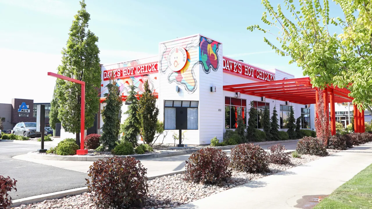 Exterior view of Dave's Hot Chicken on North Main St, Logan, UT, showcasing vibrant murals and outdoor seating.