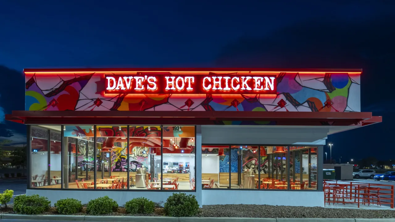 Exterior view of Dave's Hot Chicken on W. Palmetto St, Florence, SC, showcasing vibrant murals and bright red signage.
