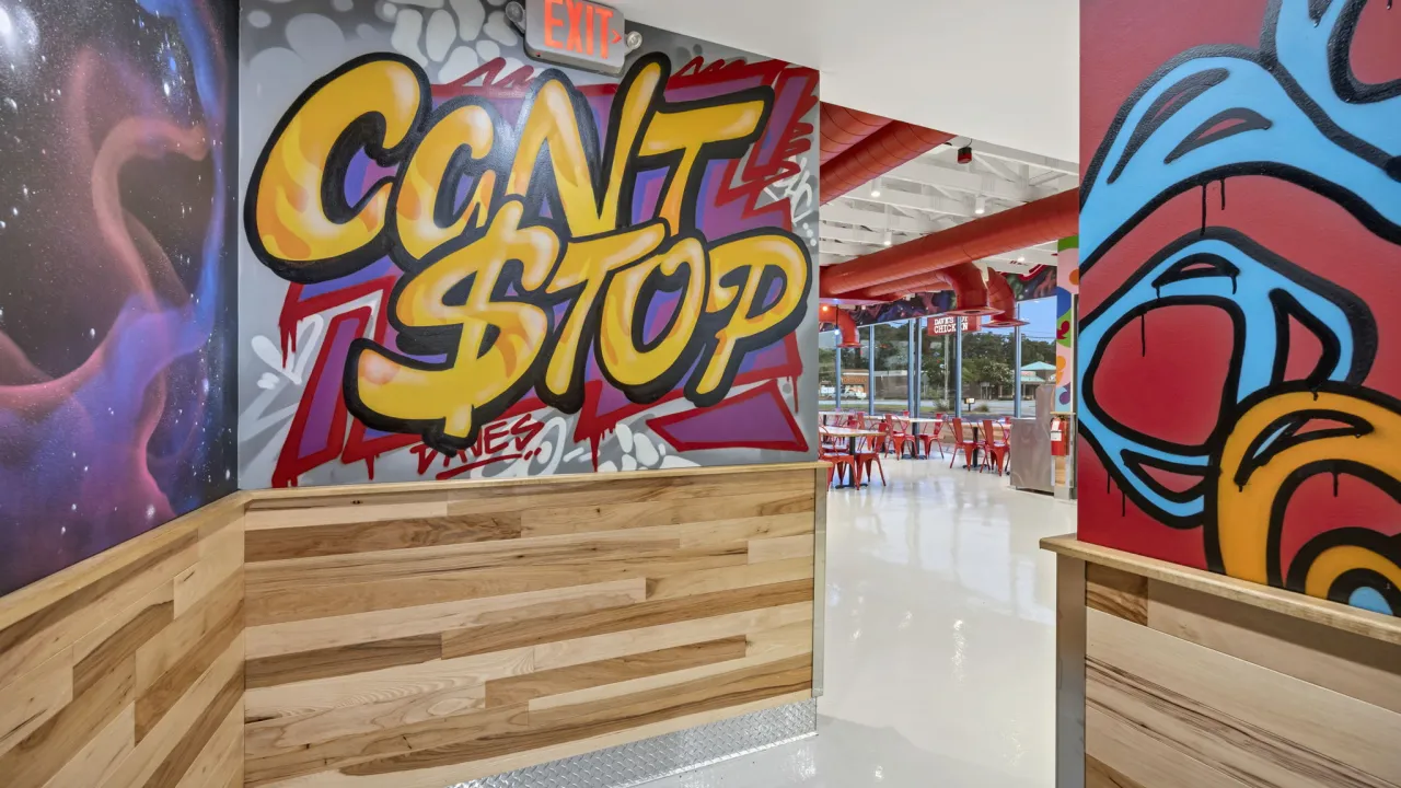 Interior view of Dave's Hot Chicken on W. Palmetto St, Florence, SC, showcasing vibrant graffiti and modern seating.