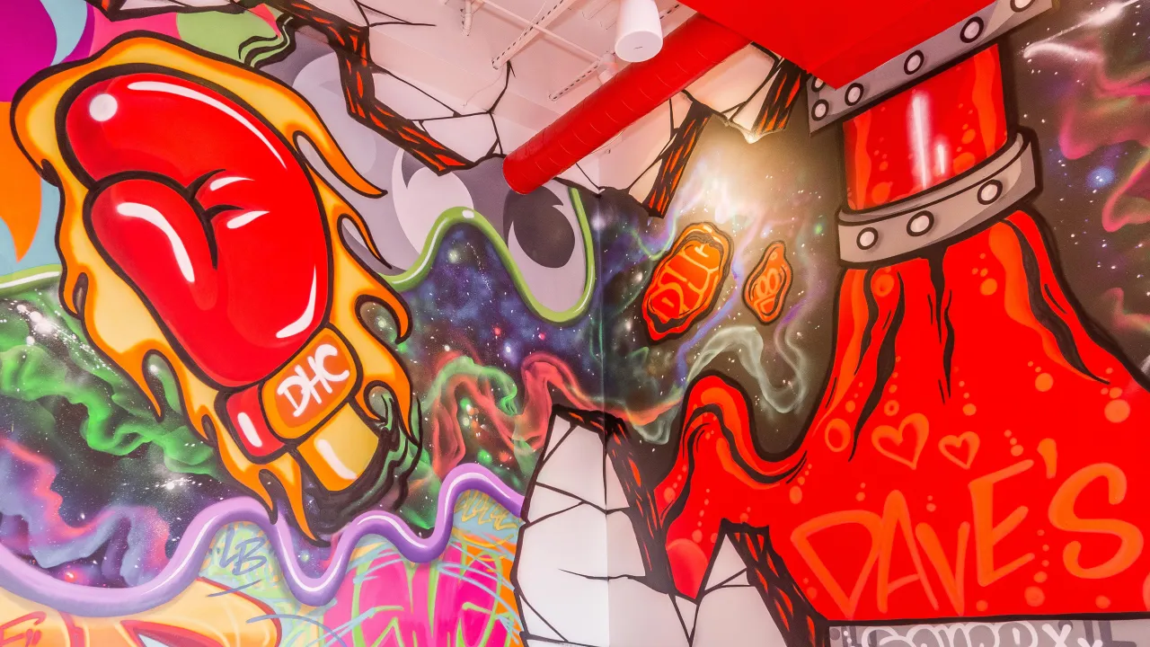 Interior mural at Dave's Hot Chicken on Shelbyville Road, Louisville, KY, showcasing vibrant graffiti art and colorful designs.