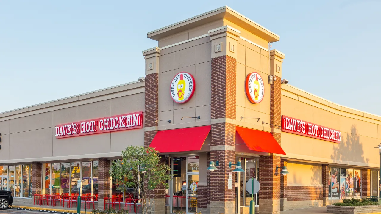 Exterior view of Dave's Hot Chicken on Shelbyville Road, Louisville, KY, showcasing bright red signage and outdoor seating.