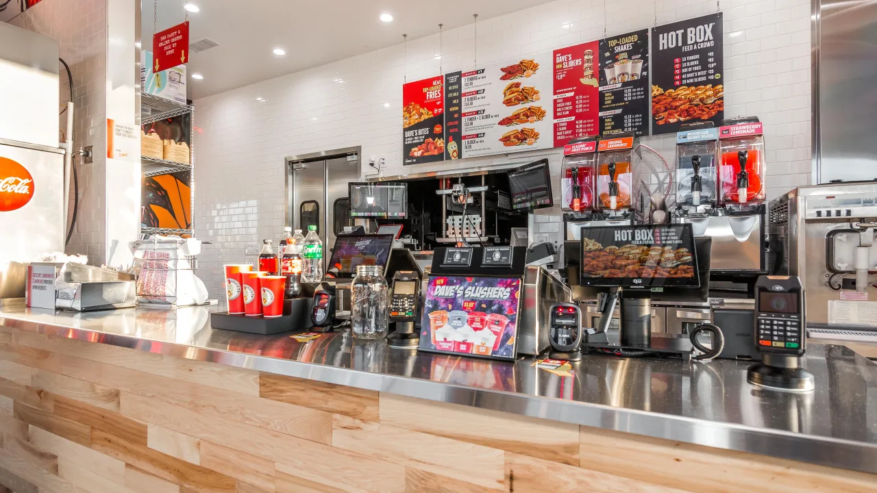 Interior view of Dave's Hot Chicken on Shelbyville Road, Louisville, KY, showcasing the vibrant counter and menu displays.
