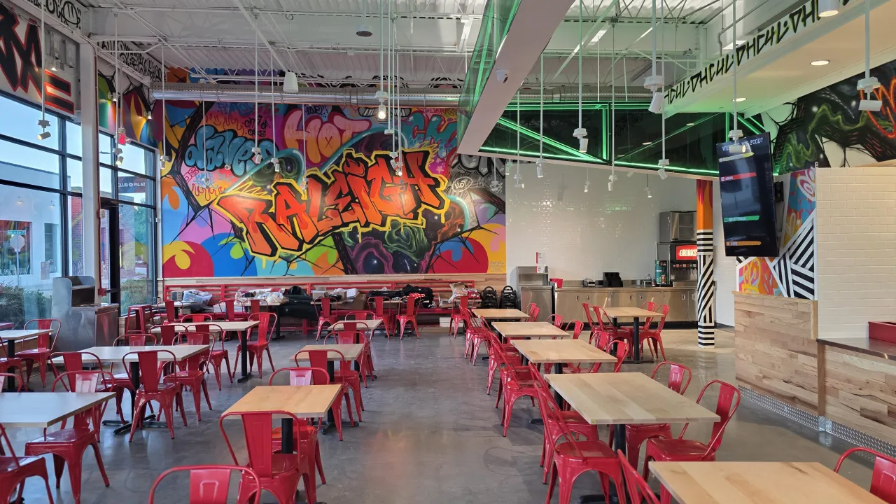 Interior view of Dave's Hot Chicken at 2920 Sherman Oak Place, Raleigh, NC, featuring vibrant murals and red seating.