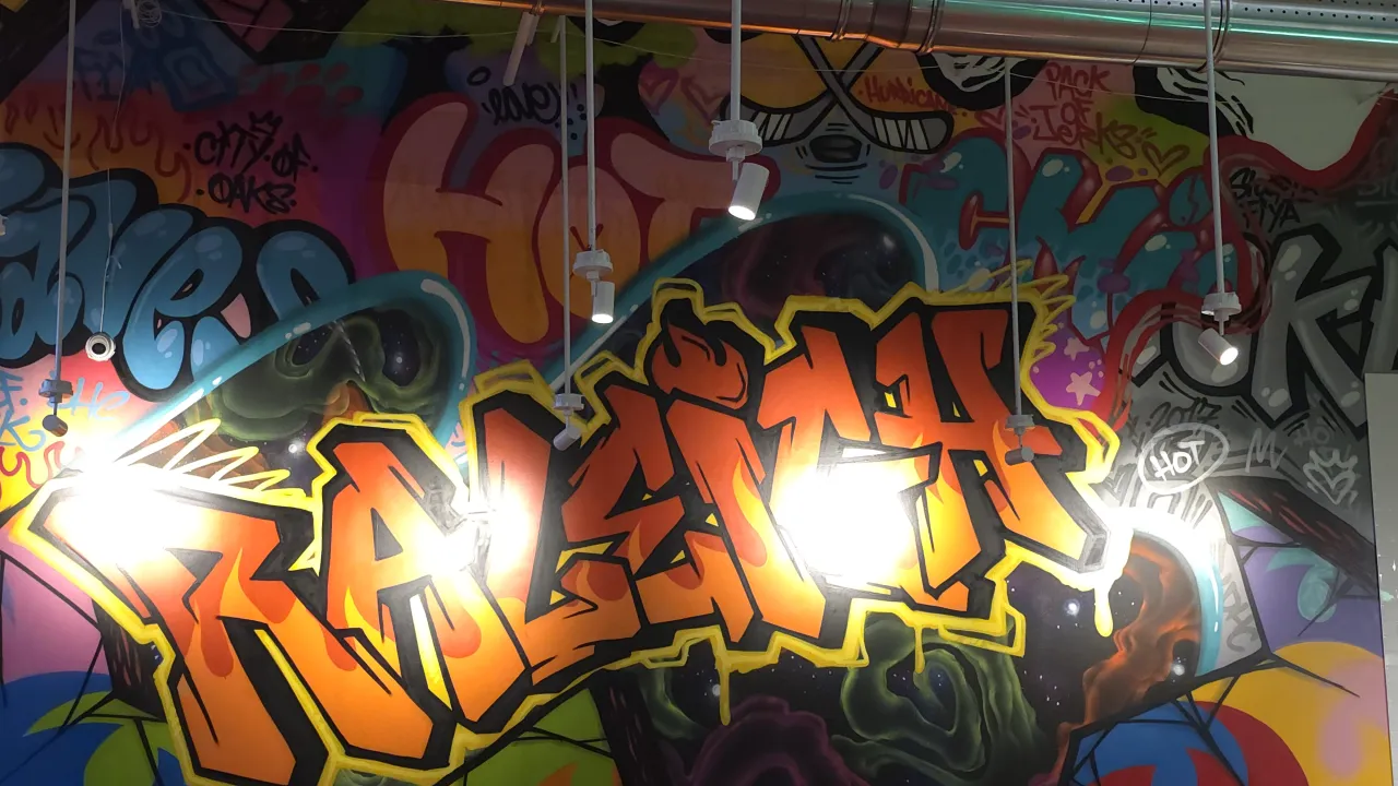 Interior view of vibrant graffiti mural at Dave's Hot Chicken on Sherman Oak Place, Raleigh, NC, featuring bold colors and lighting.