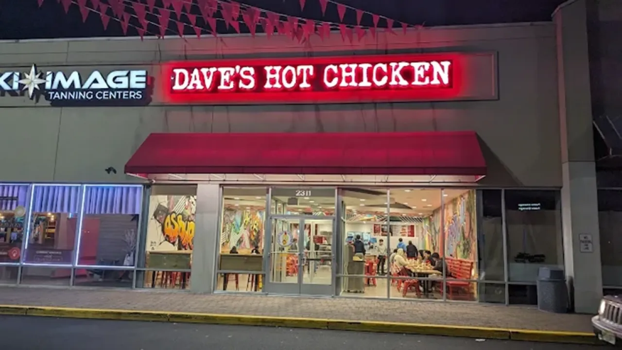 Exterior view of Dave's Hot Chicken at 2311 State Route 66 Suite 5, Ocean Township, NJ, showcasing vibrant neon signage and outdoor seating.