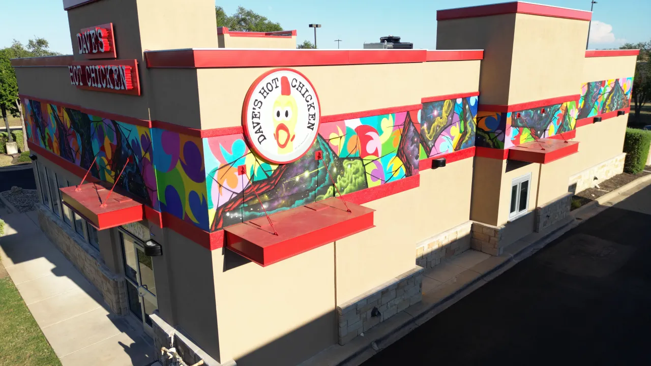 Exterior view of Dave's Hot Chicken on W. University Ave, Georgetown, TX, featuring vibrant mural and red signage.