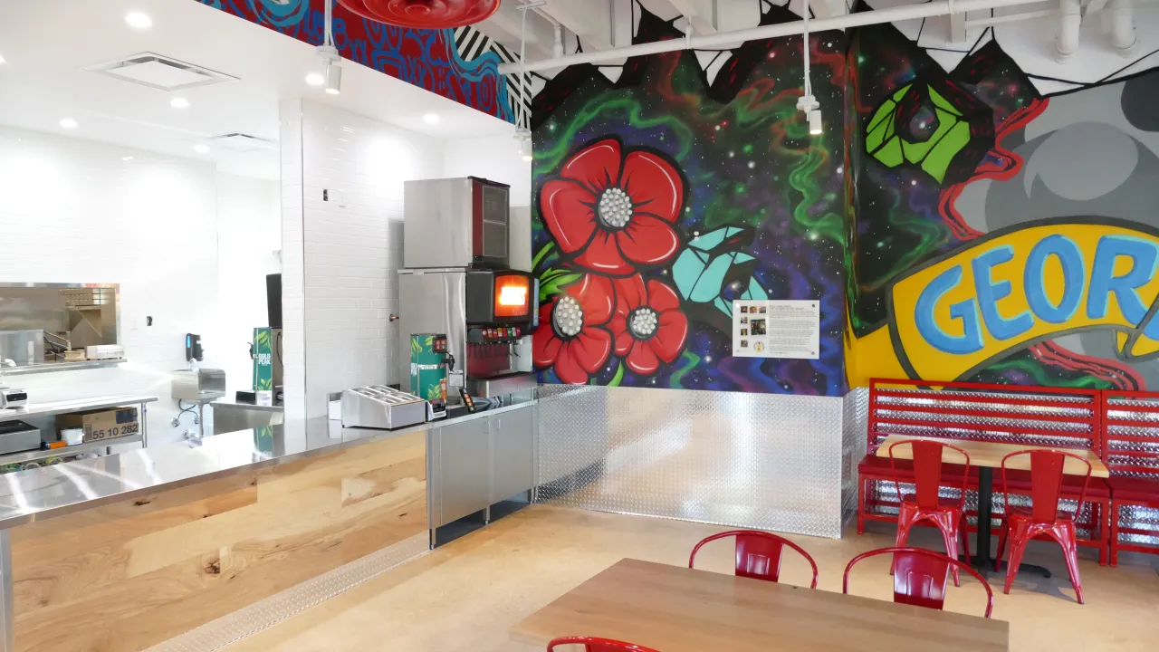 Interior view of Dave's Hot Chicken on W. University Ave, Georgetown, TX, showcasing colorful murals and vibrant seating.