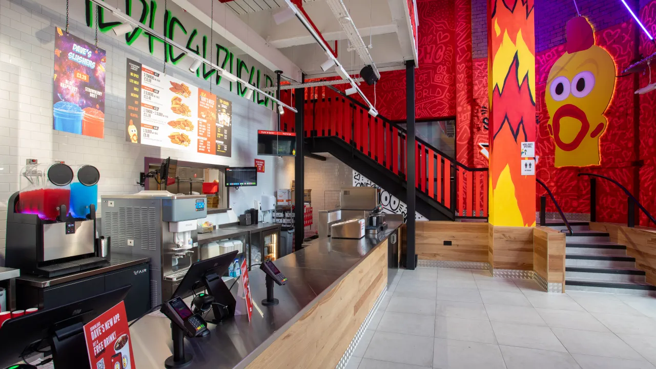 Interior view of Dave's Hot Chicken at 27 Withy Grove, Manchester, featuring vibrant murals, a service counter, and modern decor.