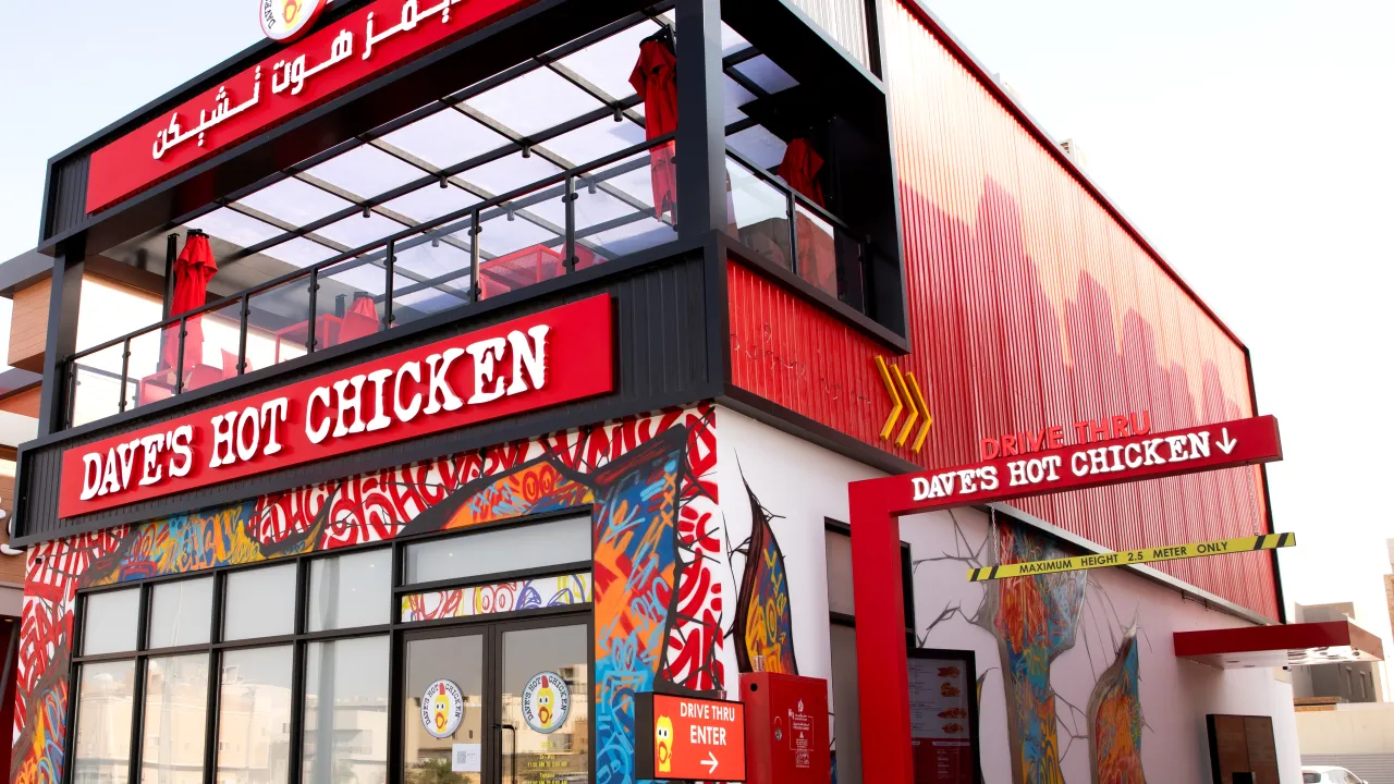 Exterior view of Dave's Hot Chicken on Anas Ibn Malik Rd, Riyadh, Saudi Arabia, showcasing vibrant murals and red signage.