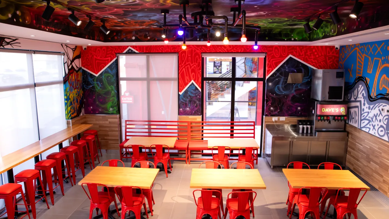 Interior view of Dave’s Hot Chicken on Anas Ibn Malik Rd, Riyadh, Saudi Arabia, showcasing vibrant murals and red seating.