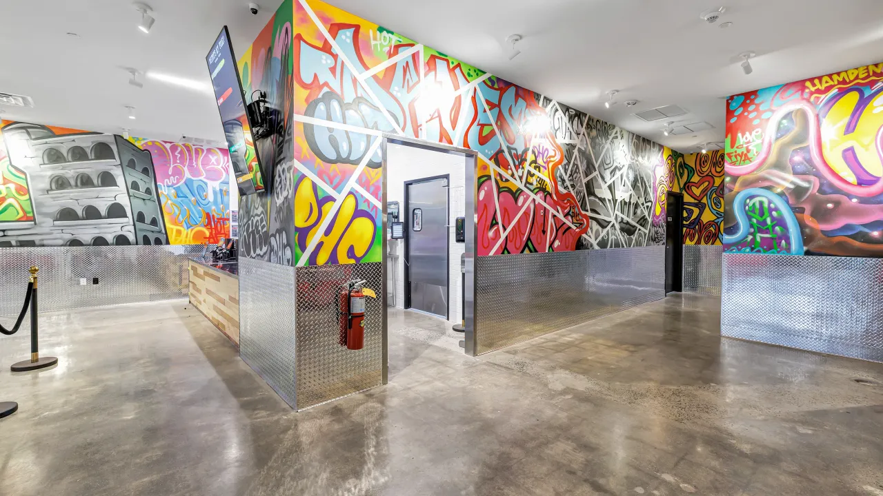 Interior view of Dave's Hot Chicken on Dixwell Ave, Hamden, CT, showcasing vibrant graffiti murals and a modern ambiance.