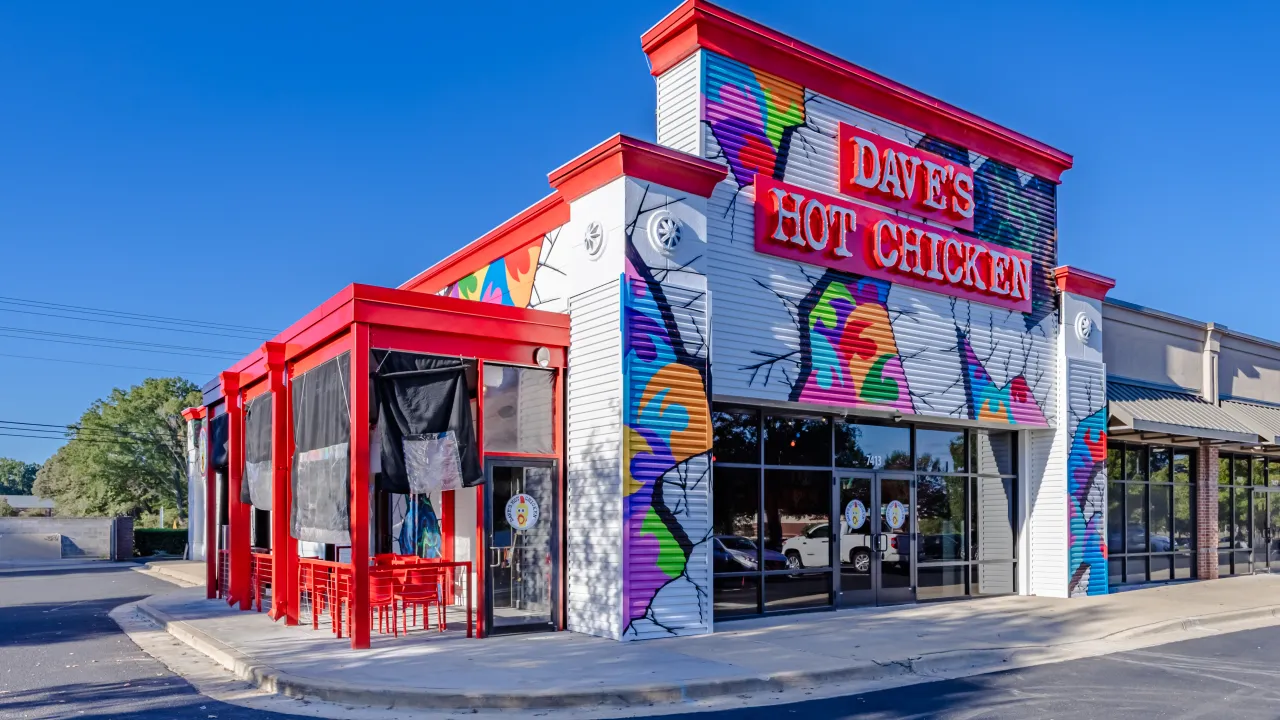 Exterior view of Dave's Hot Chicken at 7413 Eastchase Pkwy, Montgomery, AL, showcasing vibrant murals and red accents.