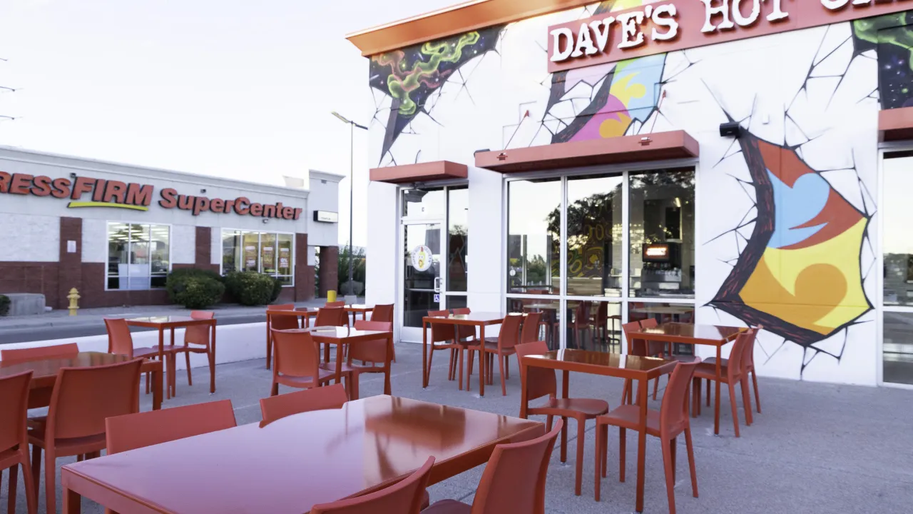 Exterior view of Dave's Hot Chicken on Ellison Rd NW, Albuquerque, NM, showcasing vibrant murals and outdoor seating.