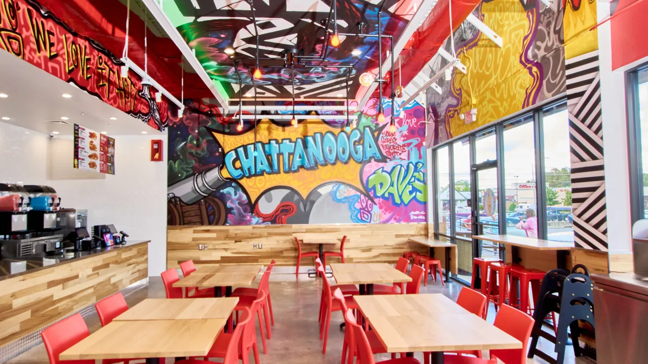 Interior view of Dave's Hot Chicken on Gunbarrel Rd, Chattanooga, TN, showcasing vibrant murals and modern seating.