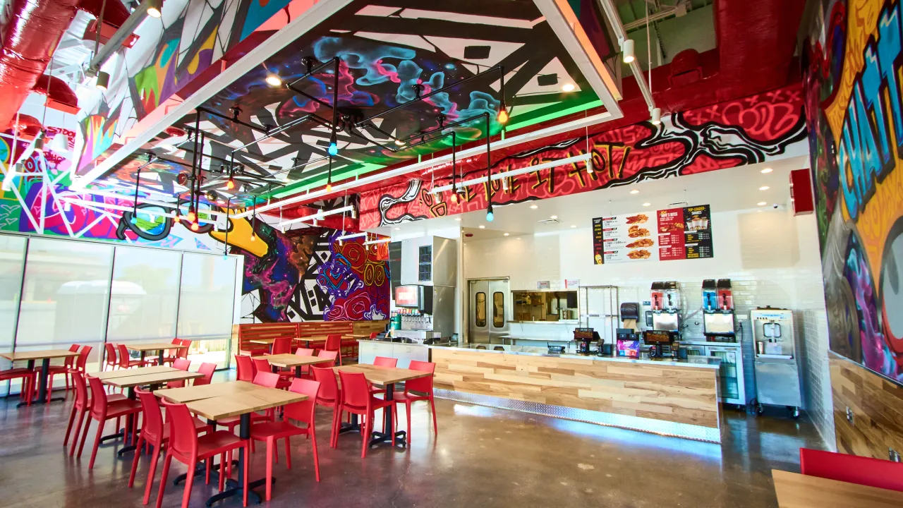 Interior view of Dave's Hot Chicken at 2266 Gunbarrel Rd, Chattanooga, TN, showcasing vibrant murals and red furniture.