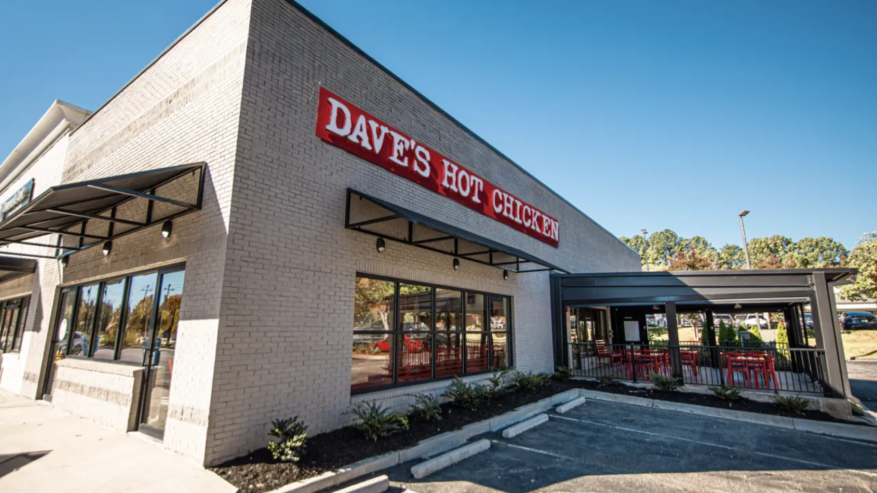 Exterior view of Dave's Hot Chicken on Haynes Bridge Rd, Alpharetta, GA, featuring red signage and outdoor seating.